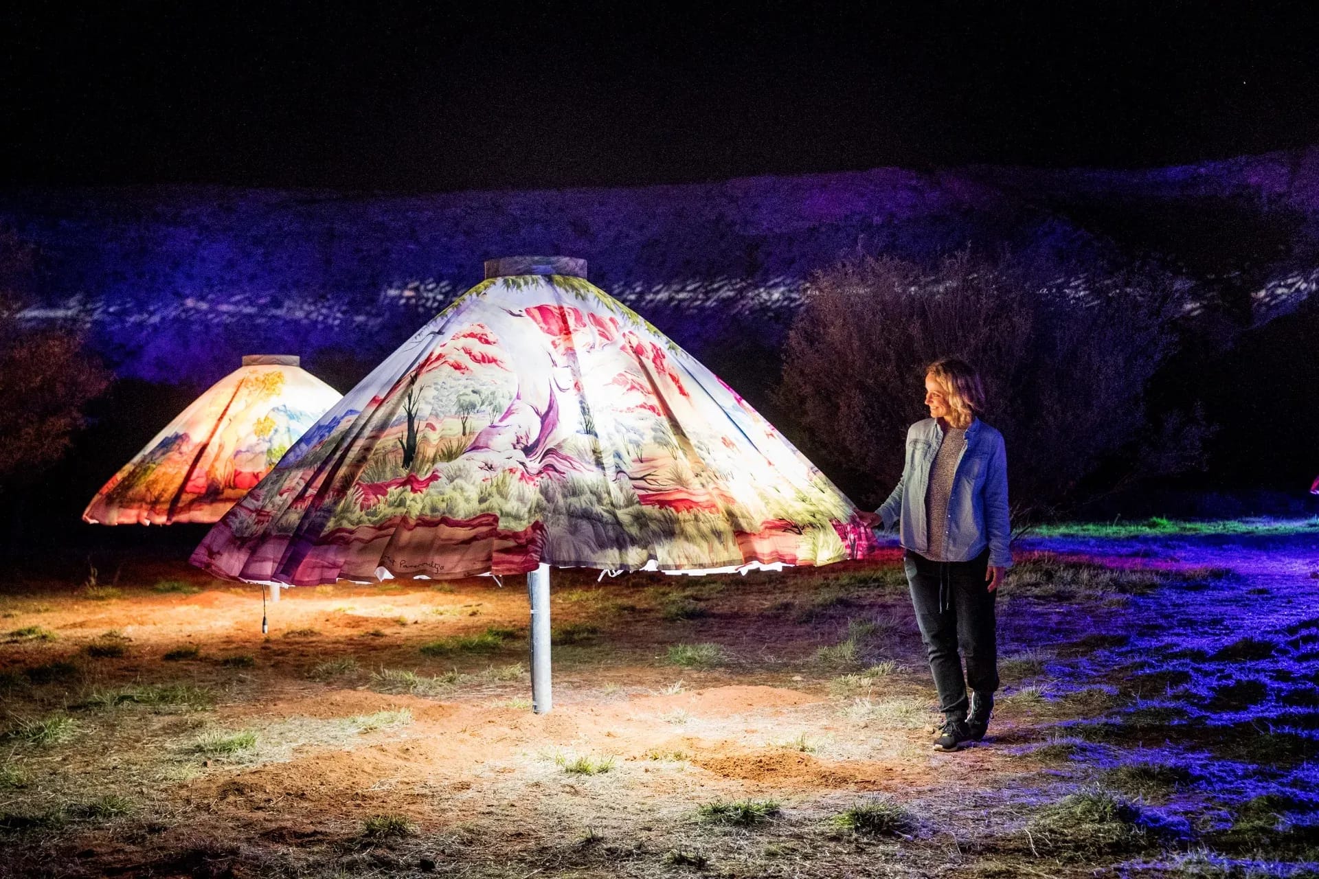 A woman standing in front of a light sculpture of an umbrella