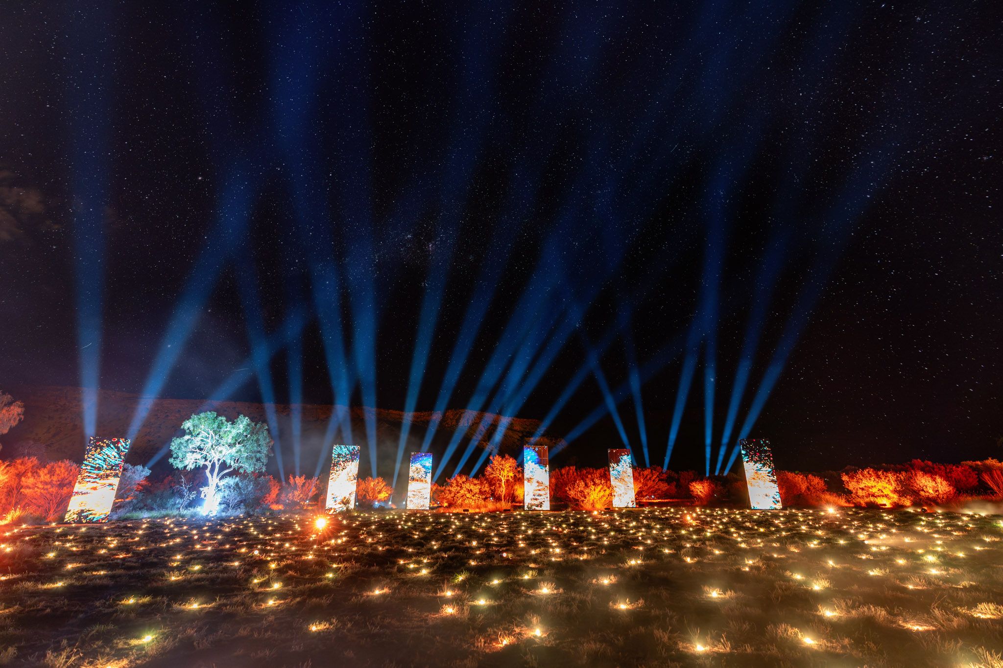 Light projections on to a mountain range with light installations in foreground