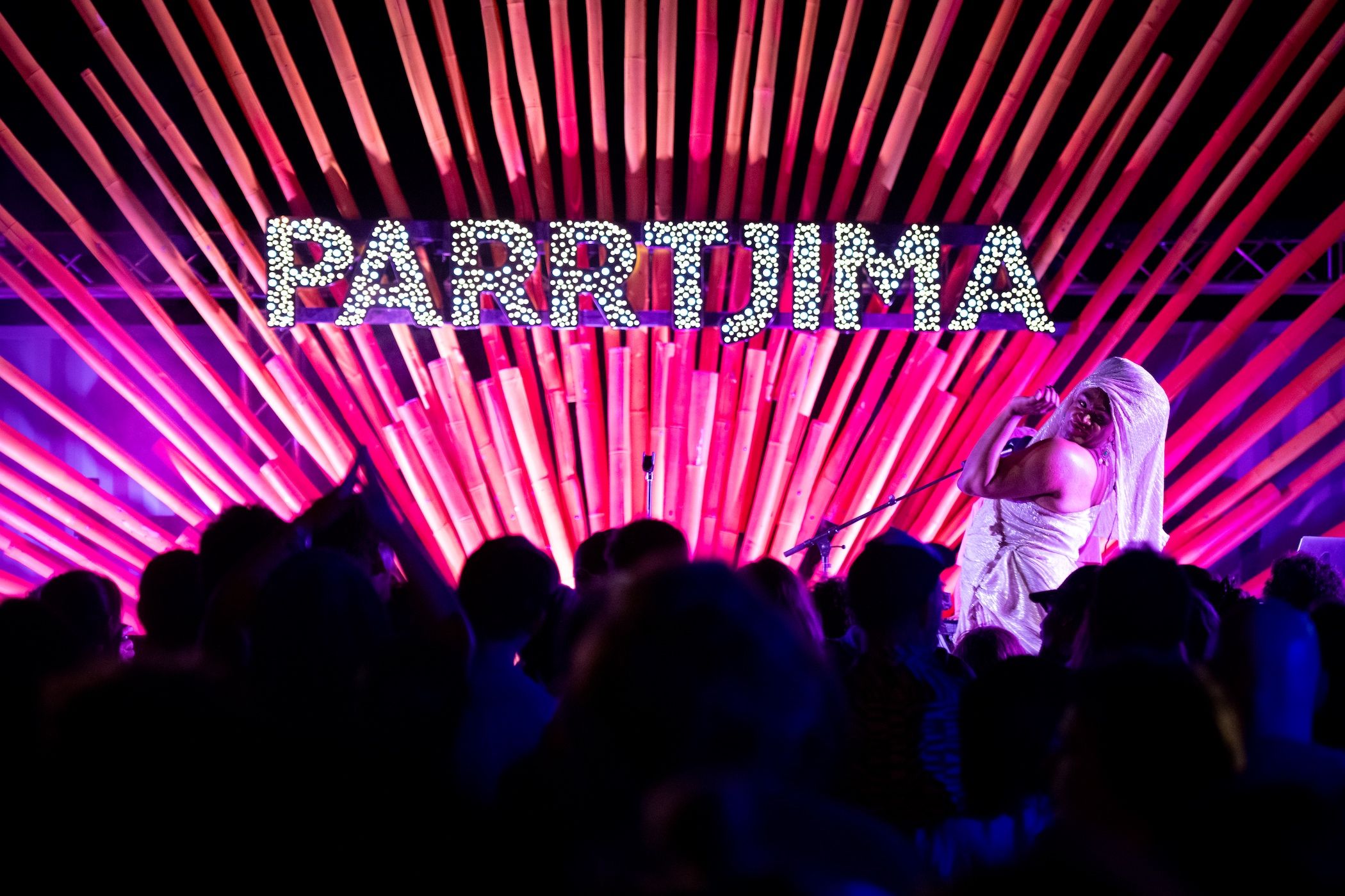 Singer with microphone on a stage with "Parrtjima" words behind her and crowd in front